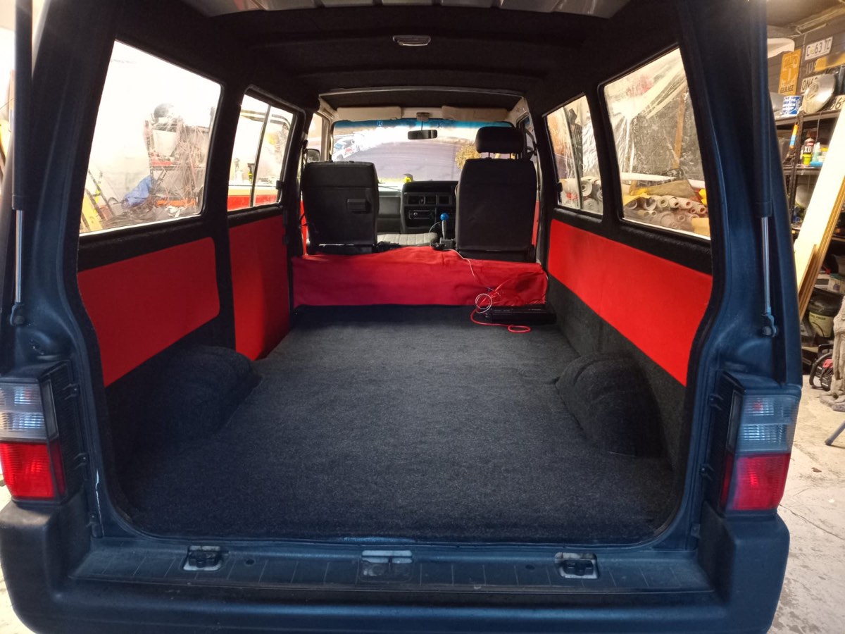 Toyota Hiace passenger van after — custom red-and-grey panel trim with full grey carpet floor